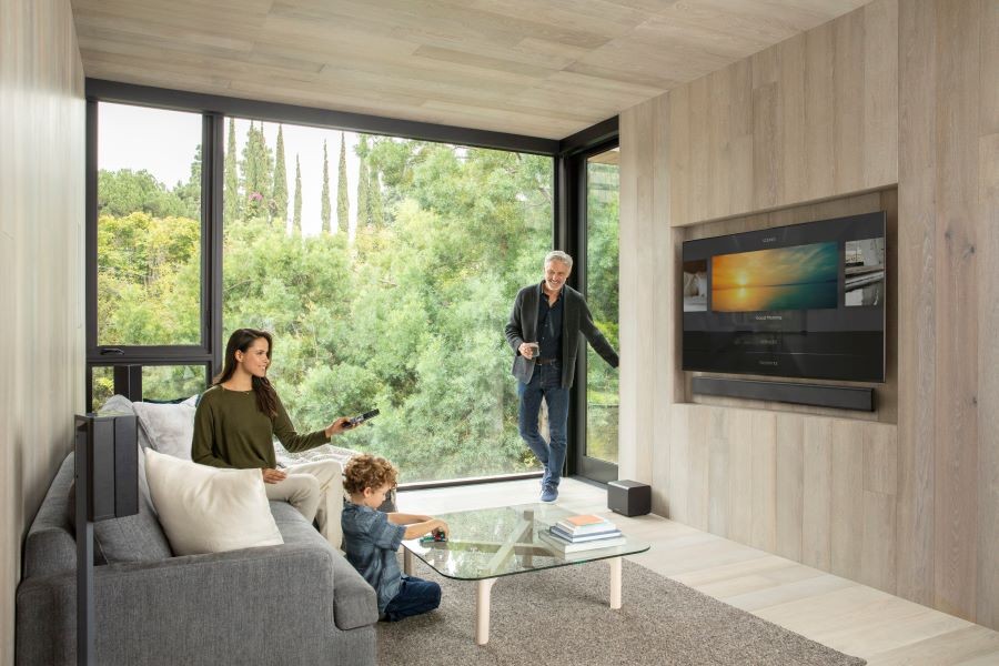 A family in a living room using the Savant Pro remote to select audio on the TV.