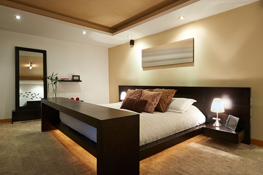 Warm lighting illuminates a bedroom with smart home lighting and speakers.