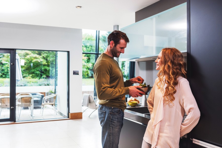 A happy couple stands together in a kitchen.