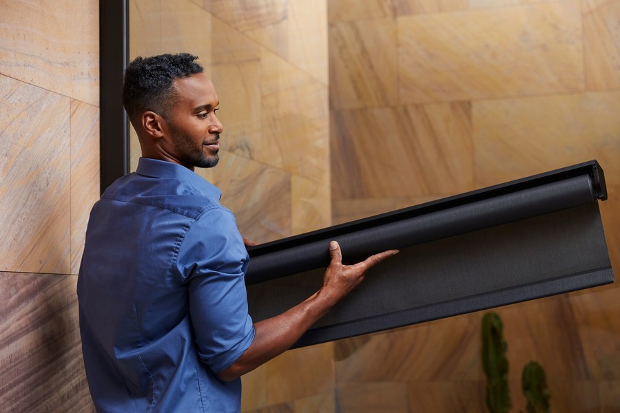 Techician carrying black roller shades for an installation. 