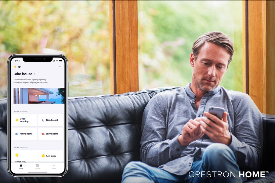 A man operates his smart home from a smartphone app; a screenshot of the app is superimposed to the left. 