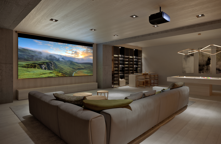 A luxury media room with sofa seating, a large screen, and hidden audio speakers.